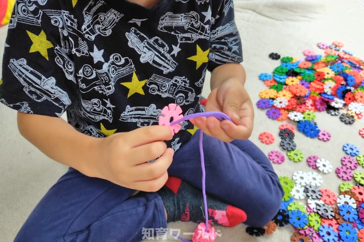 5歳の息子がジスターと付属のひもを使ってひも通し遊びをしているところの写真